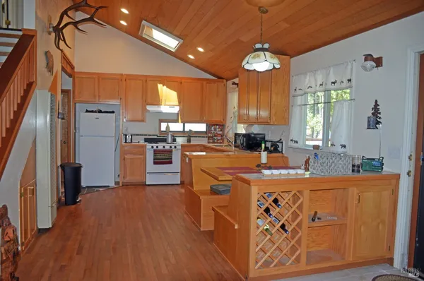 a kitchen with stainless steel appliances granite countertop a refrigerator a sink dishwasher a stove and a dining table with wooden floor