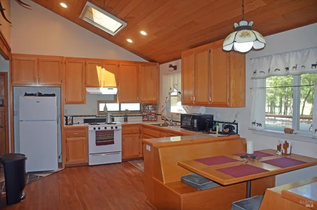 a kitchen with stainless steel appliances granite countertop a stove refrigerator a sink dishwasher and microwave with wooden floor