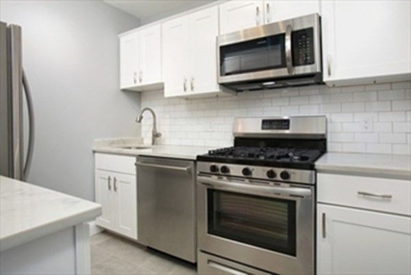 a kitchen with stainless steel appliances a stove a microwave a sink and cabinets