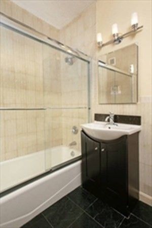 a bathroom with a sink and mirror with bathtub