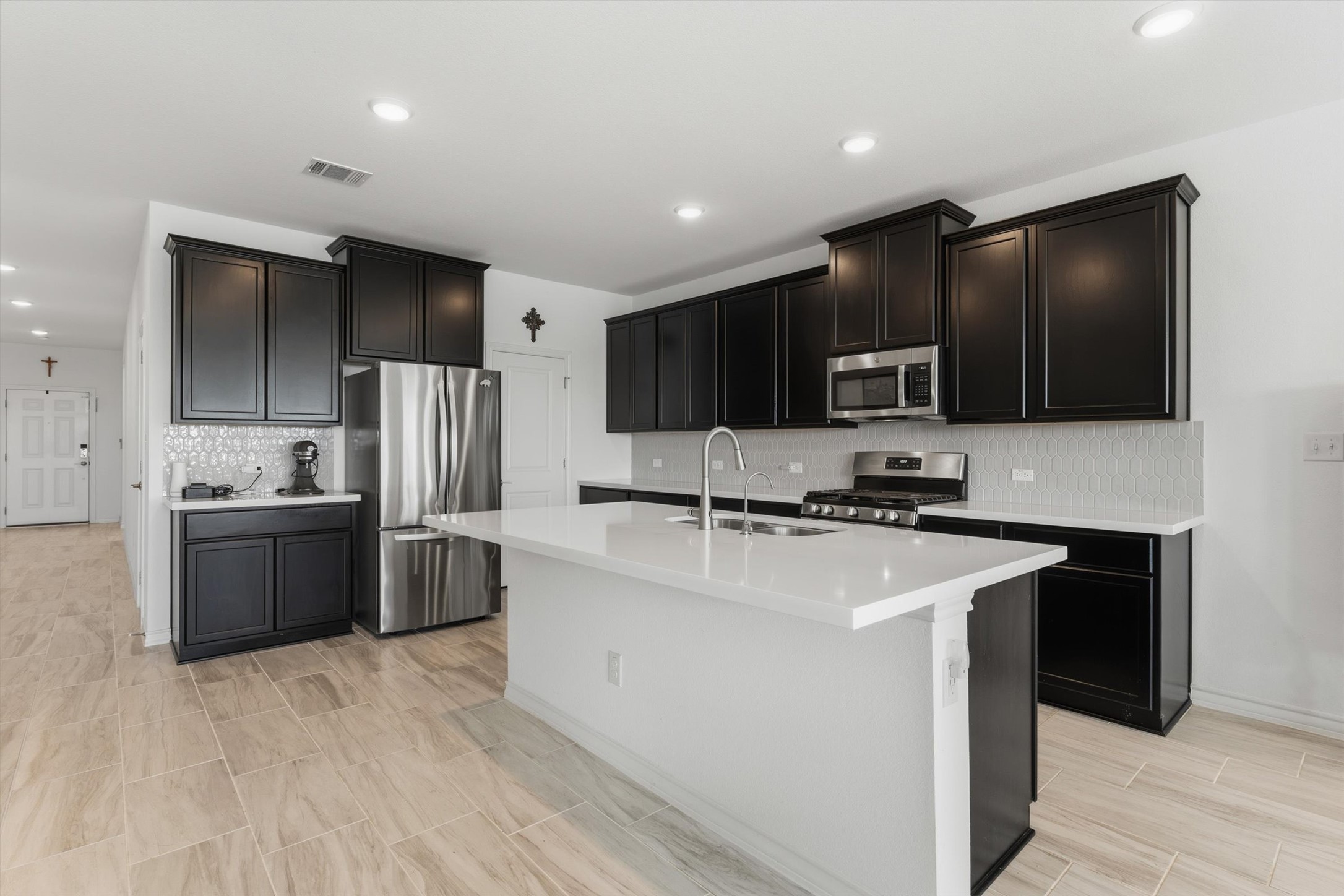 1000 Moose Road Hutto, TX 78634 - Photo 10 of 29 Kitchen with stainless steel appliances, tasteful backsplash, an island with sink, recessed lighting, and light stone countertops