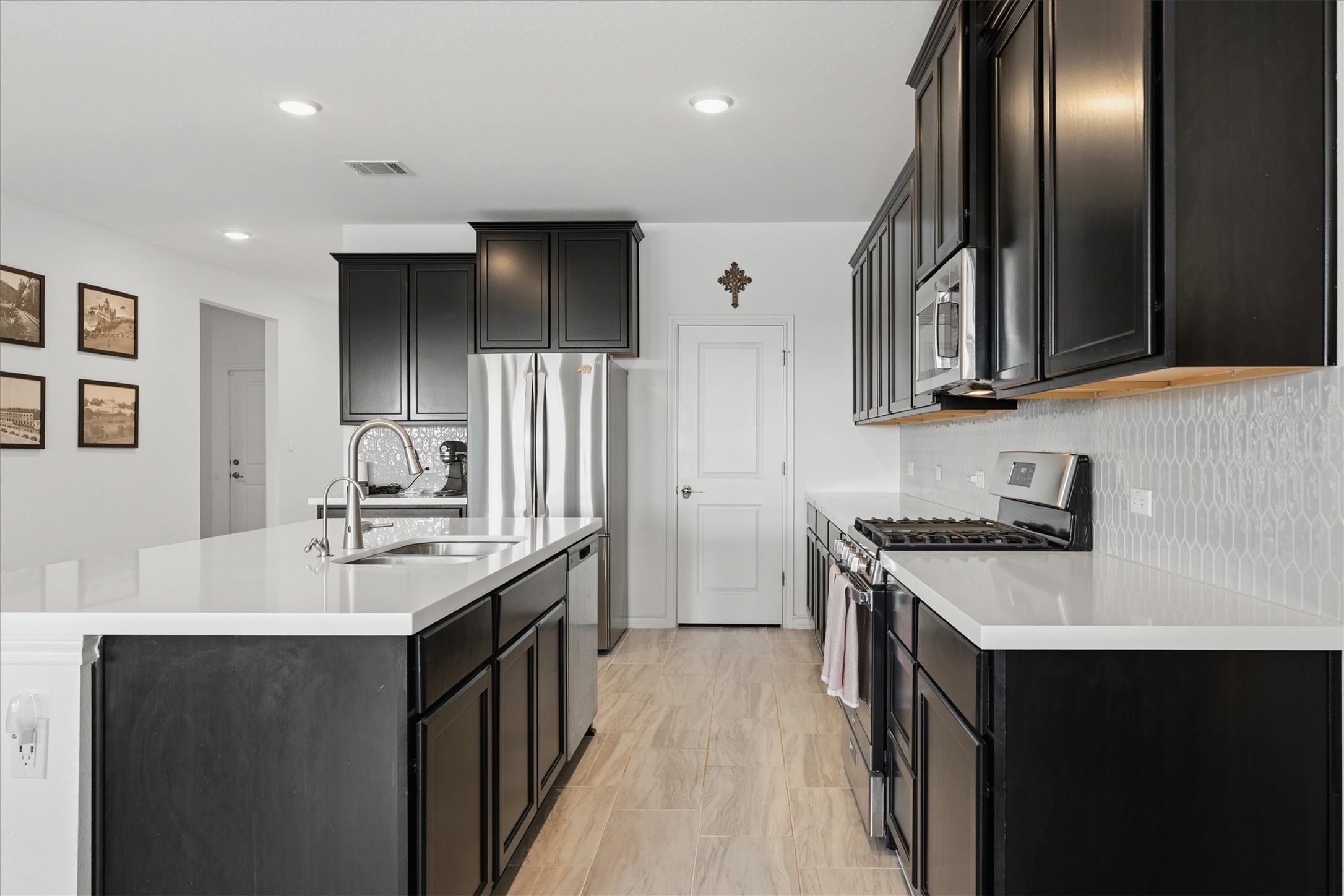 1000 Moose Road Hutto, TX 78634 - Photo 11 of 29 Kitchen featuring dark cabinetry, stainless steel appliances, backsplash, a center island with sink, and recessed lighting