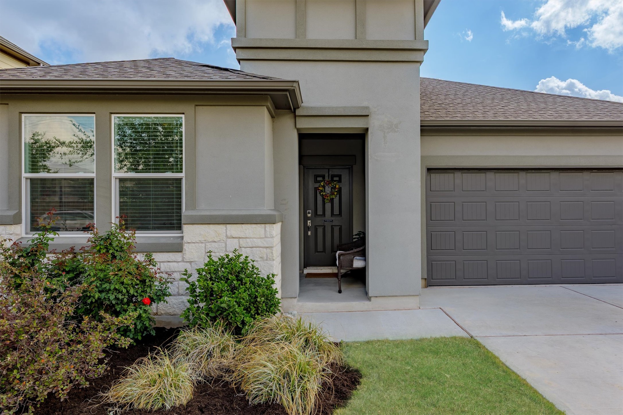 1000 Moose Road Hutto, TX 78634 - Photo 3 of 29 Entrance to property with concrete driveway, a shingled roof, an attached garage, stucco siding, and stone siding