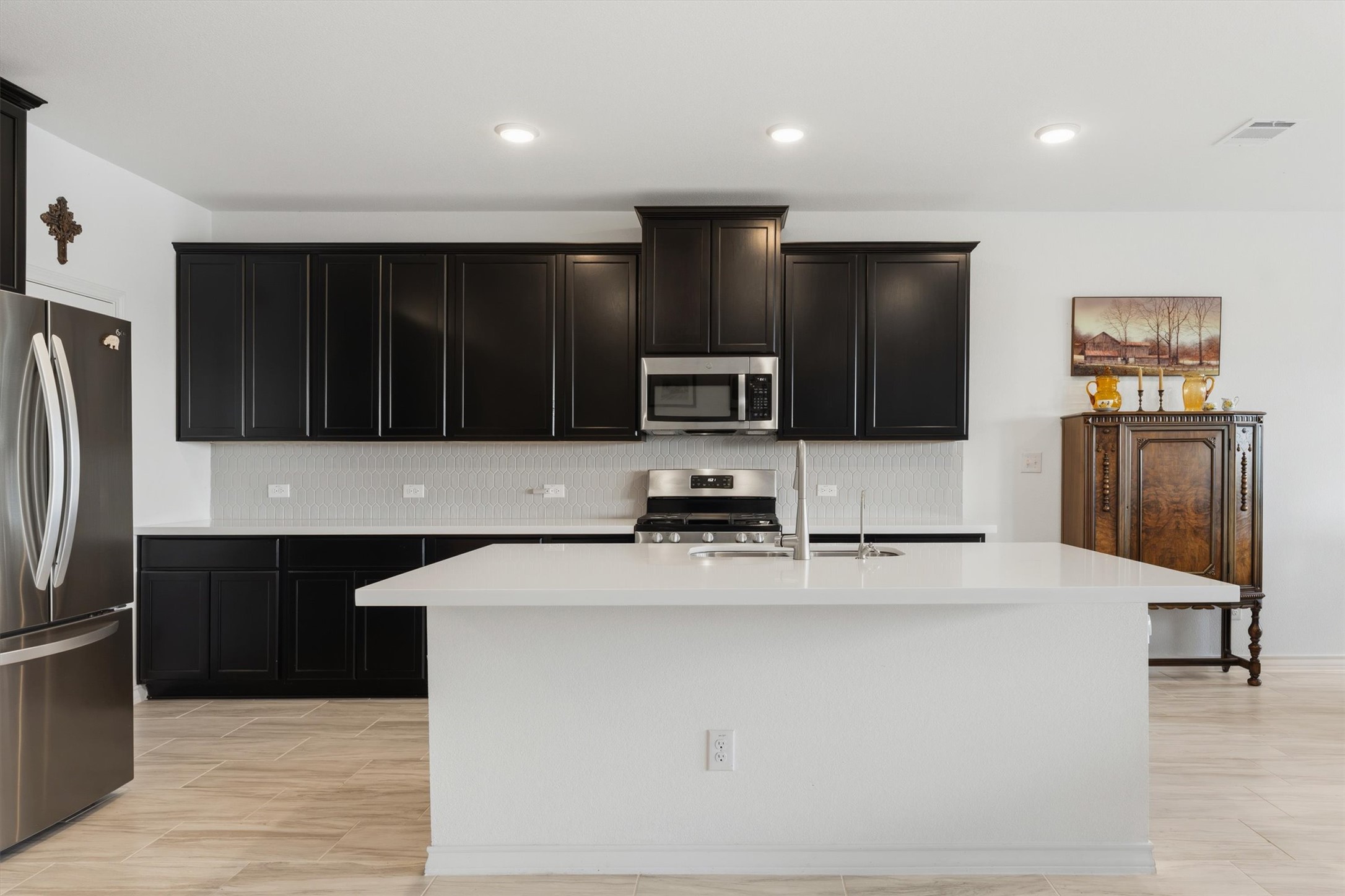 1000 Moose Road Hutto, TX 78634 - Photo 9 of 29 Kitchen with stainless steel appliances, a center island with sink, light stone countertops, recessed lighting, and wood tiled floors