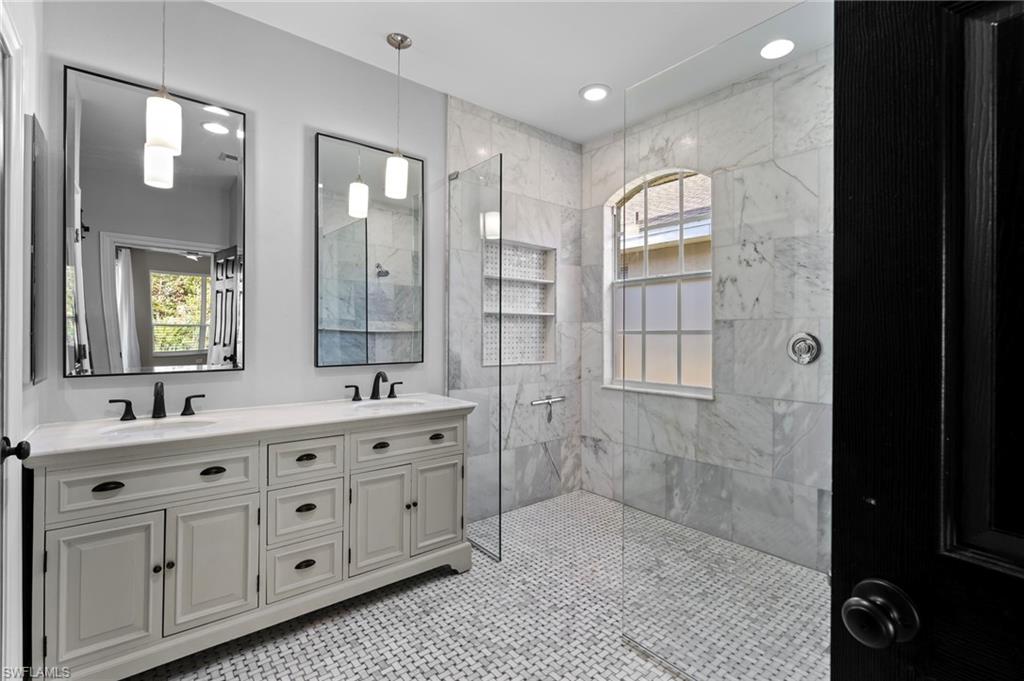 22932 Forest Ridge Drive Estero, FL 33928 - Photo 20 of 41 a bathroom with a double vanity sink a large mirror a shower and