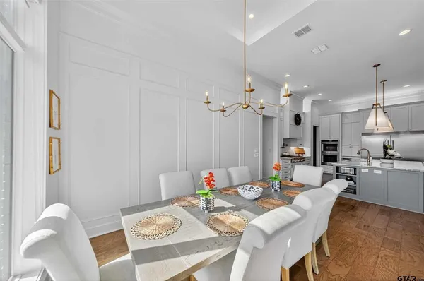 a view of a dining room and livingroom with furniture wooden floor a rug a chandelier