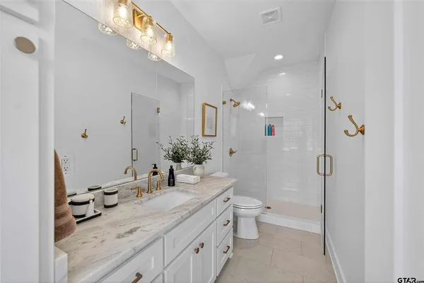a bathroom with a granite countertop sink a toilet a mirror and shower