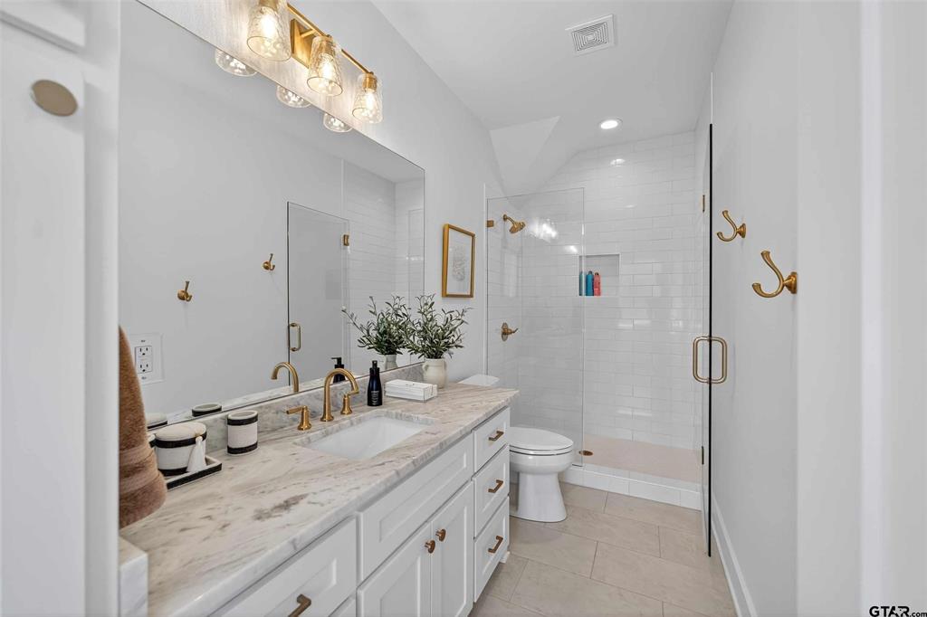1572 Maple Lane Tyler, TX 75703 - Photo 28 of 40 a bathroom with a granite countertop sink a toilet a mirror and shower