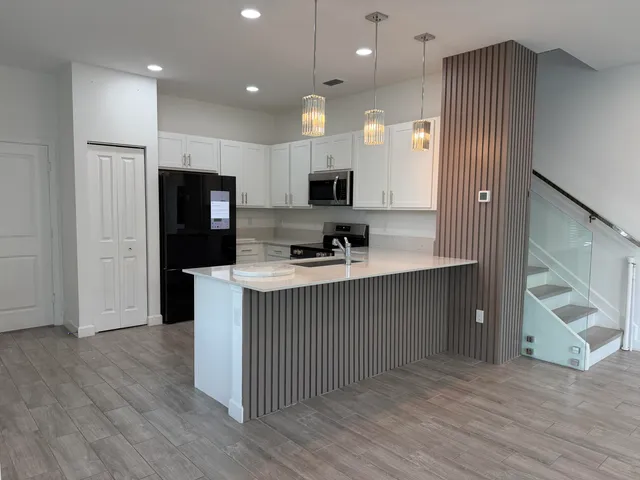 an open kitchen with a refrigerator and a stove top oven