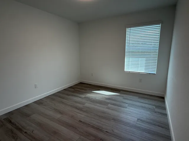 an empty room with wooden floor and a window