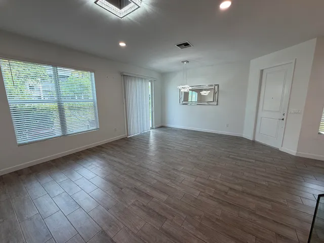 an empty room with wooden floor and windows