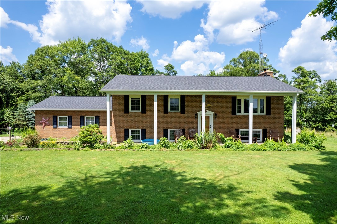 Raised ranch with a front lawn, brick siding, a chimney, and roof with shingles