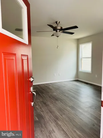 an empty room with wooden floor closet and windows