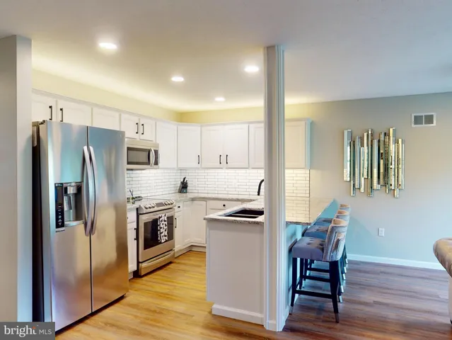 a kitchen with stainless steel appliances a refrigerator a stove a sink a dining table and chairs