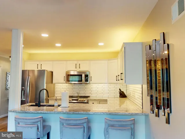 a kitchen with stainless steel appliances kitchen island granite countertop a refrigerator and cabinets