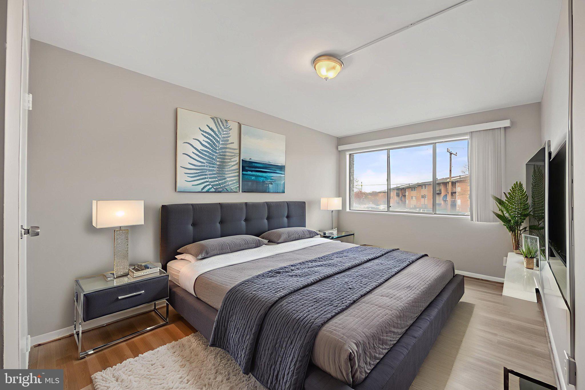 a bedroom with a large bed and a flat tv screen on dresser