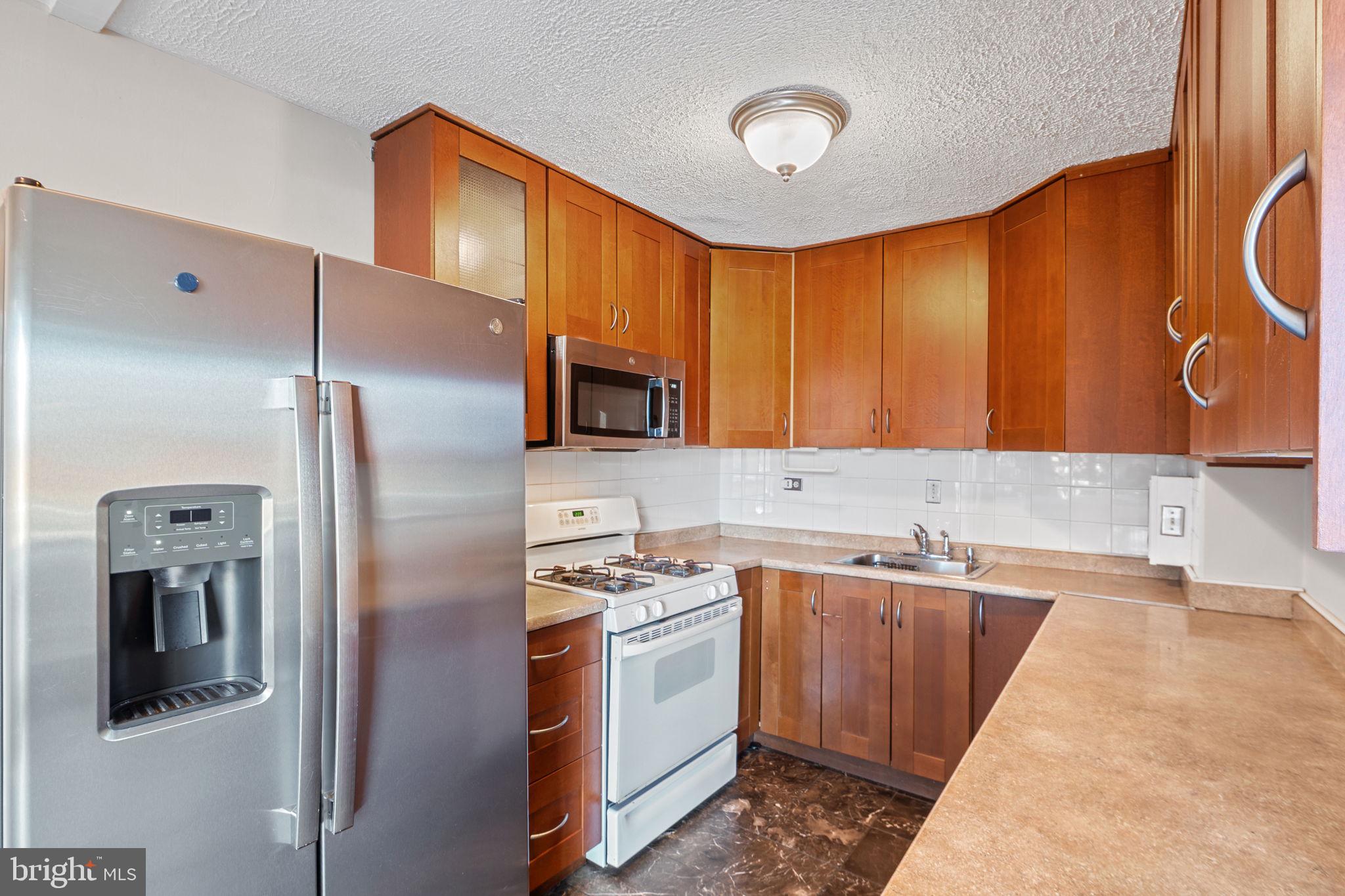 431 North Armistead Street, Unit 211 Alexandria, VA 22312 - Photo 18 of 27 a kitchen with stainless steel appliances a sink stove and refrigerator