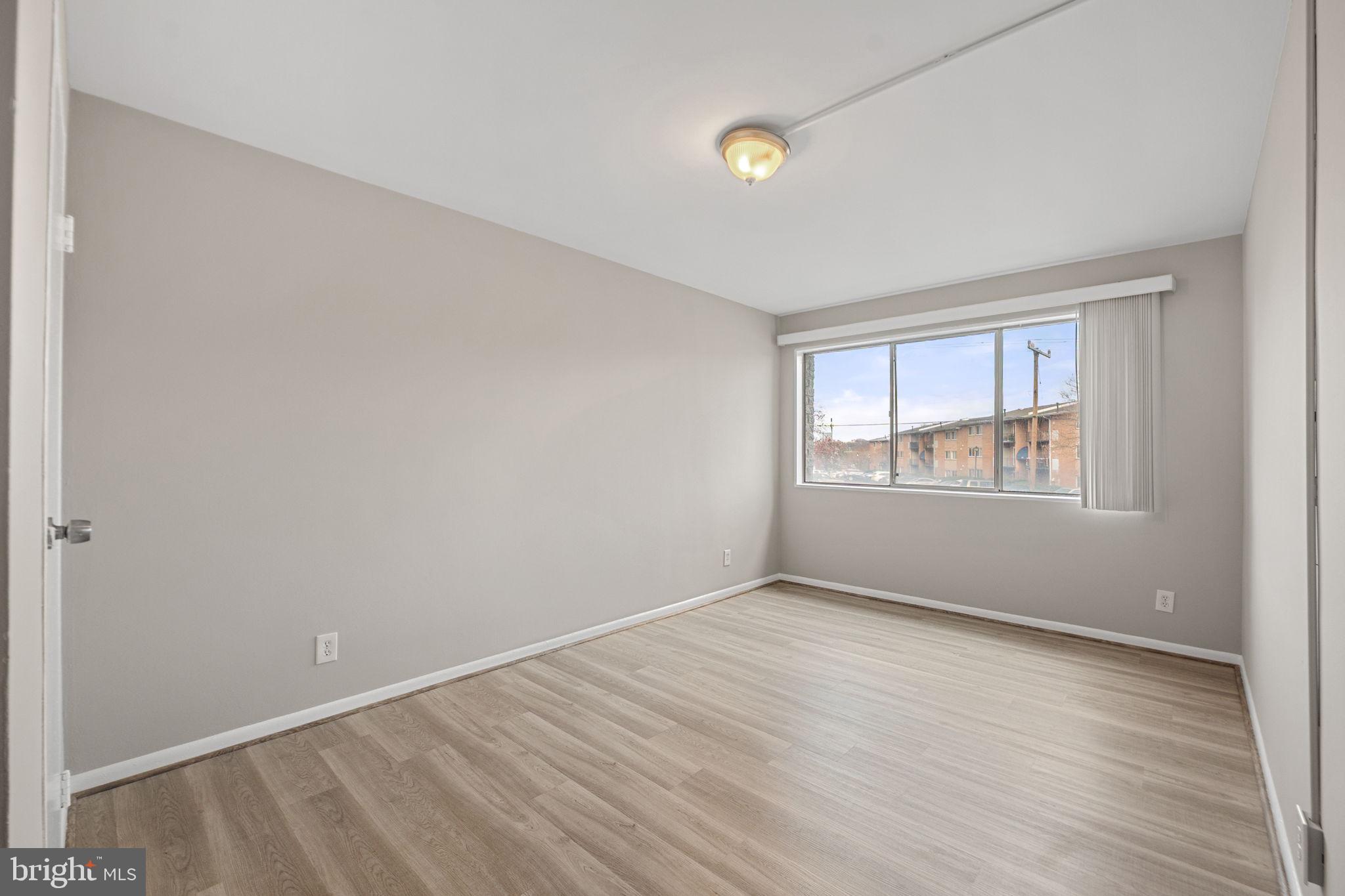 431 North Armistead Street, Unit 211 Alexandria, VA 22312 - Photo 2 of 27 a view of an empty room with wooden floor and a window