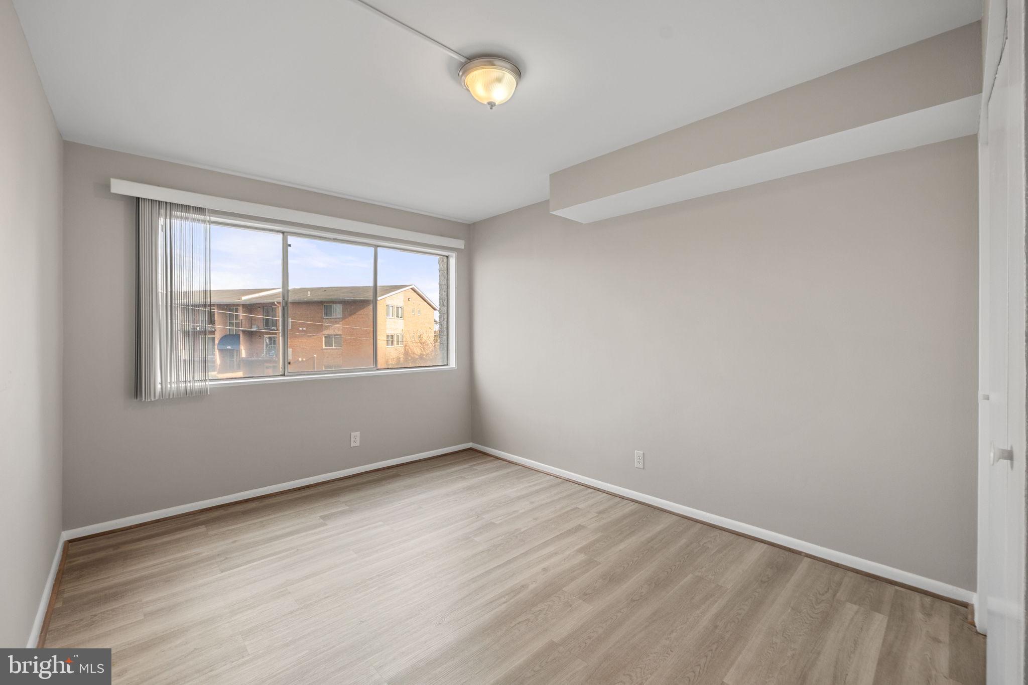 431 North Armistead Street, Unit 211 Alexandria, VA 22312 - Photo 7 of 27 an empty room with wooden floor and windows