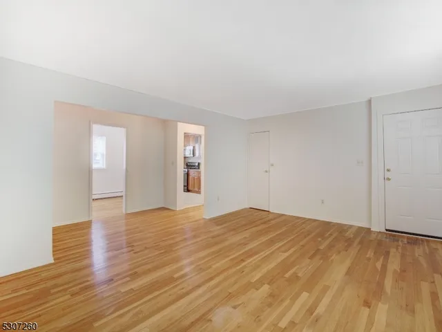 a view of empty room with wooden floor and fan