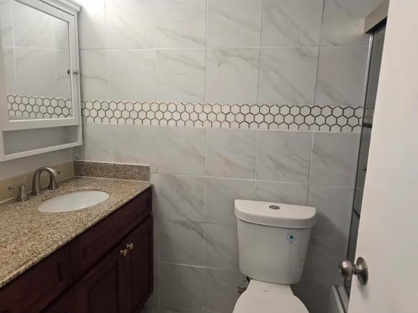 a bathroom with a granite countertop toilet and a sink