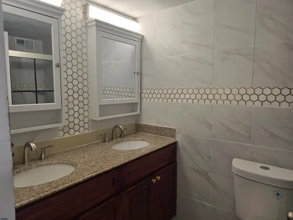 a bathroom with a granite countertop sink a toilet and mirror
