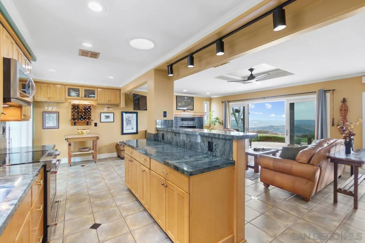 14770 High Valley Road Poway, CA 92064 - Photo 11 of 32 a kitchen with stainless steel appliances granite countertop a couch and a living room view