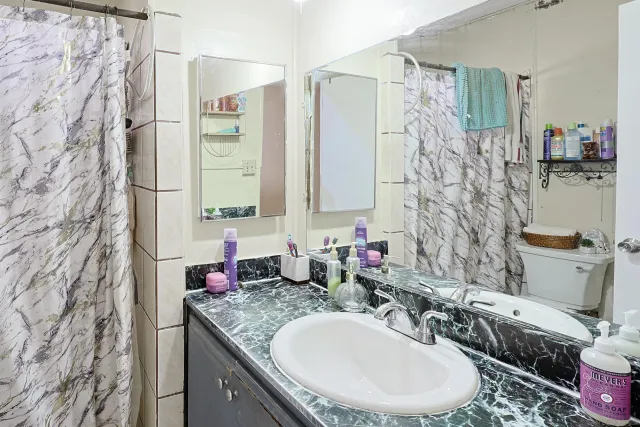 a bathroom with a granite countertop sink a toilet and a shower