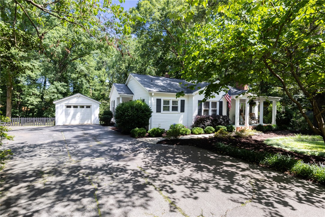 203 Augusta Road Clemson, SC 29631 - Photo 2 of 31 White siding and dark shutters provide a striking facade, complemented by lush greenery.