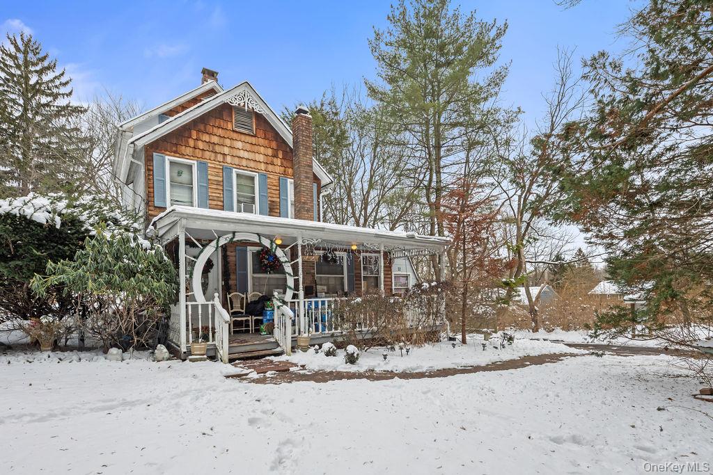 View of front of house with a chimney and covered porch