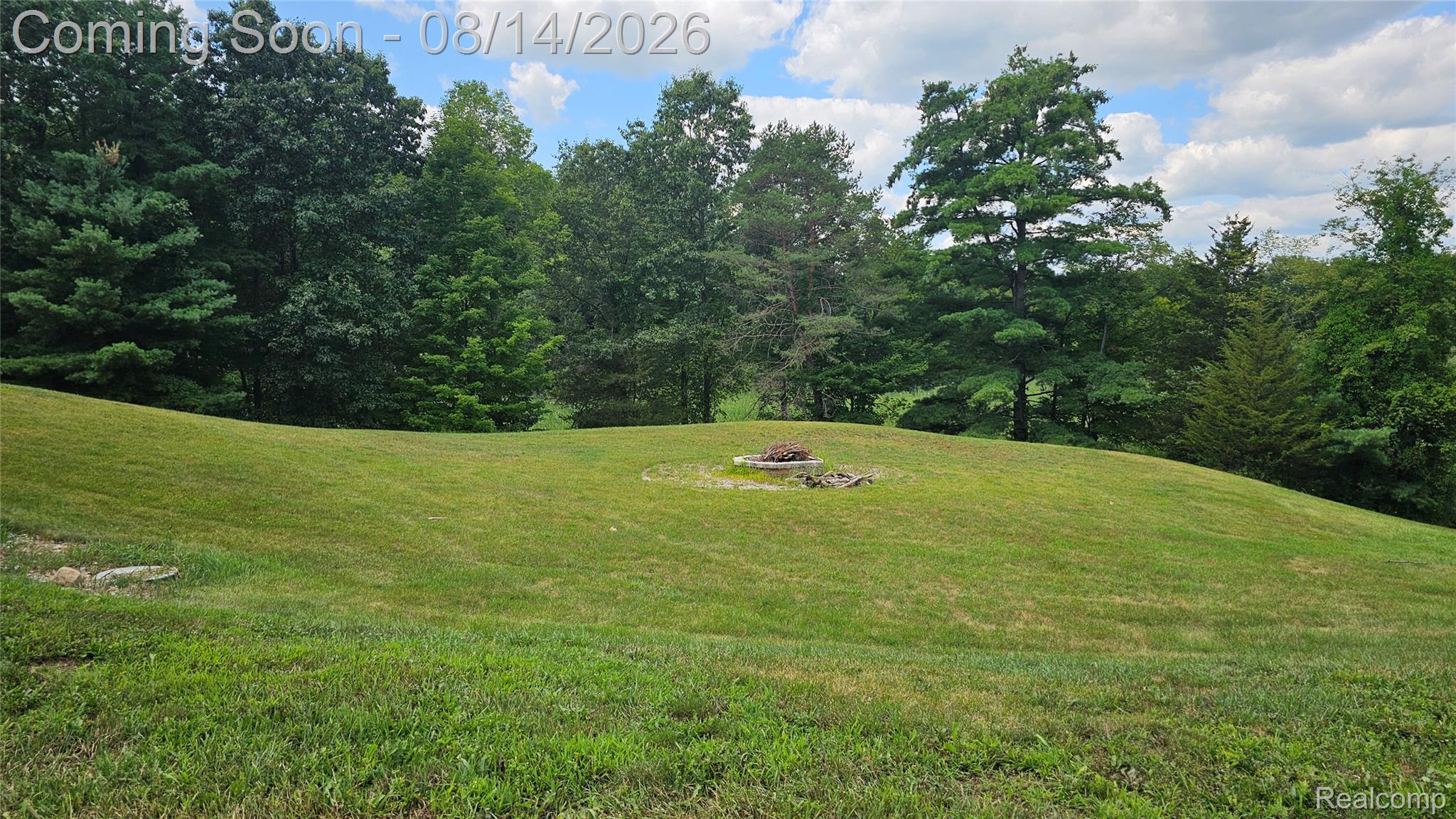 7966 Pettysville Road Pinckney, MI 48169 - Photo 42 of 43 Expansive lawn featuring a built-in fire pit with stone surround and mature trees