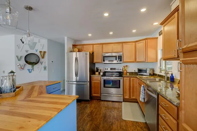 a kitchen with stainless steel appliances granite countertop a refrigerator a sink and wooden cabinets