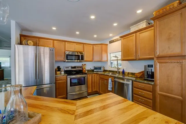 a living room with stainless steel appliances kitchen island granite countertop furniture and a wooden floor