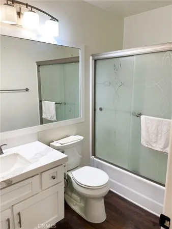 a bathroom with a granite countertop bathtub shower sink vanity and toilet