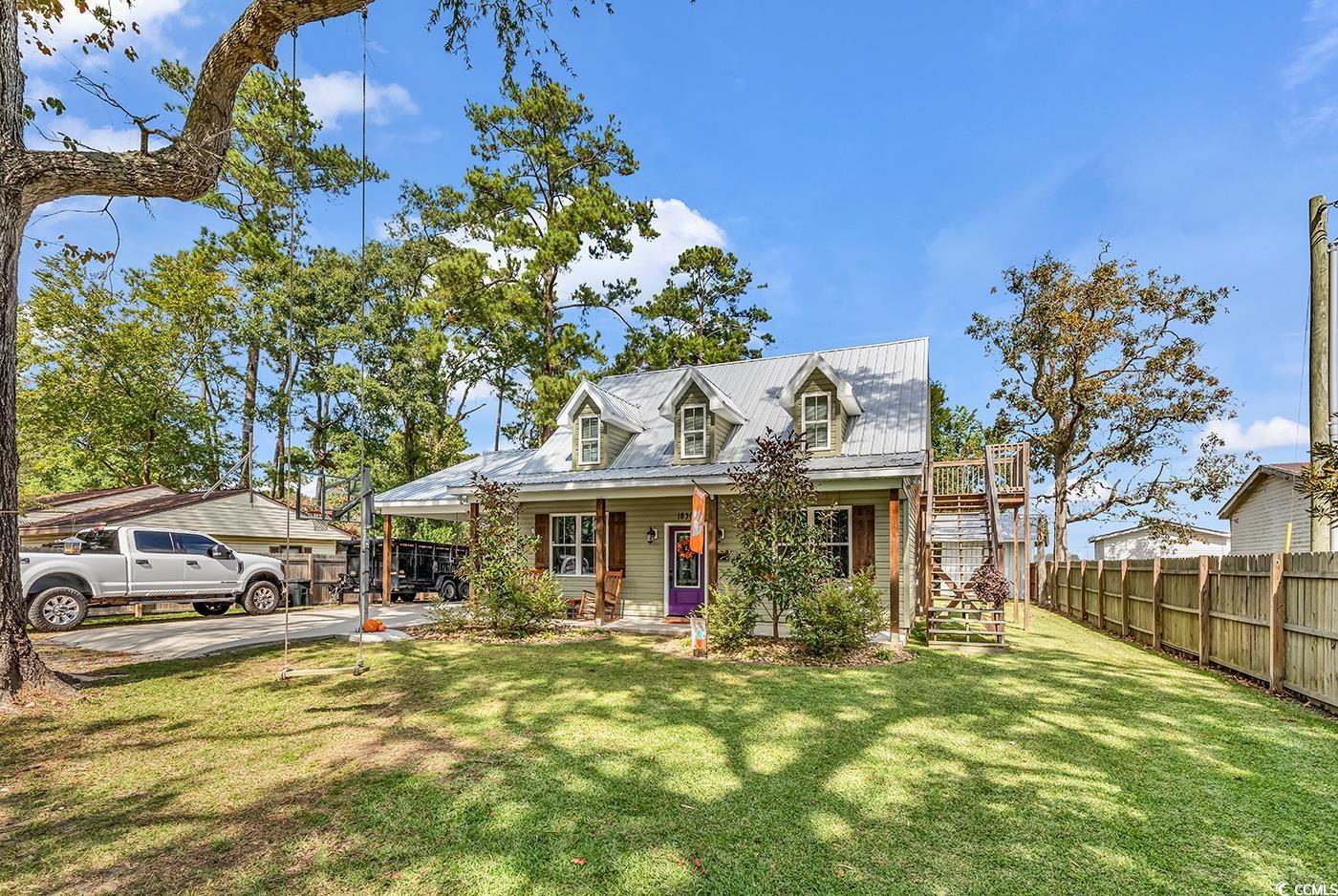 Cape cod home with a porch, stairway, and an attached carport