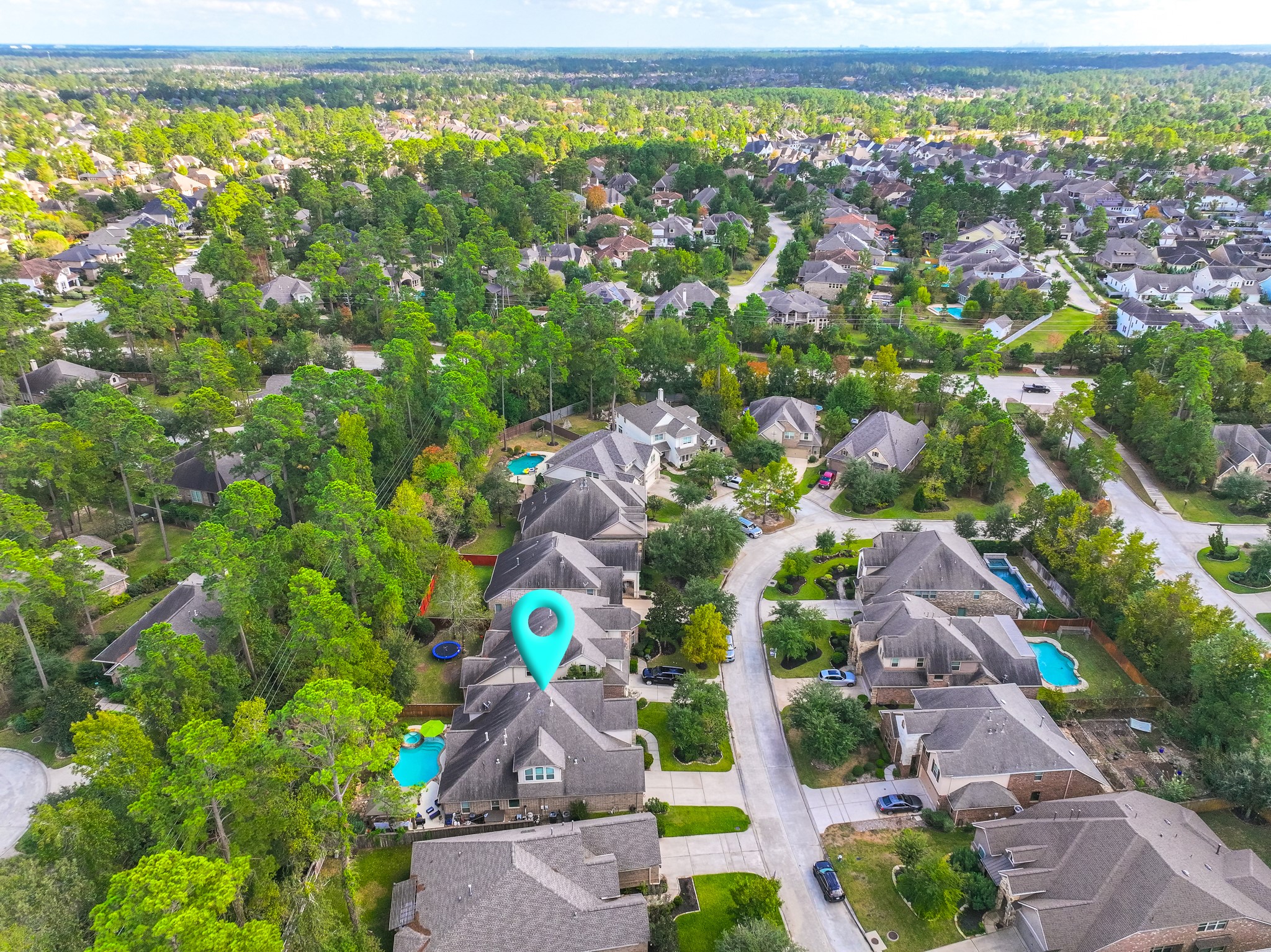 30 Fury Ranch Place The Woodlands, TX 77375 - Photo 6 of 47 This aerial photo showcases a peaceful suburban neighborhood with tree-lined streets and spacious homes. The highlighted property features a backyard pool, and the area is surrounded by lush greenery, offering a serene and private setting.
