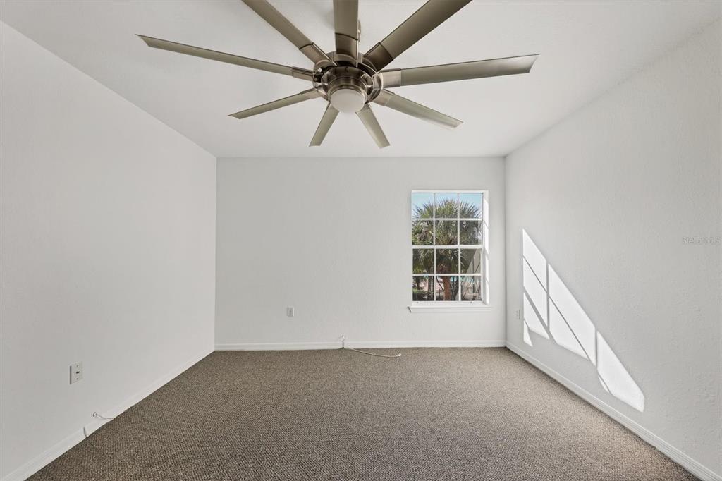 8932 Manor Loop, Unit 207 Lakewood Ranch, FL 34202 - Photo 16 of 33 an empty room with chandelier fan and windows