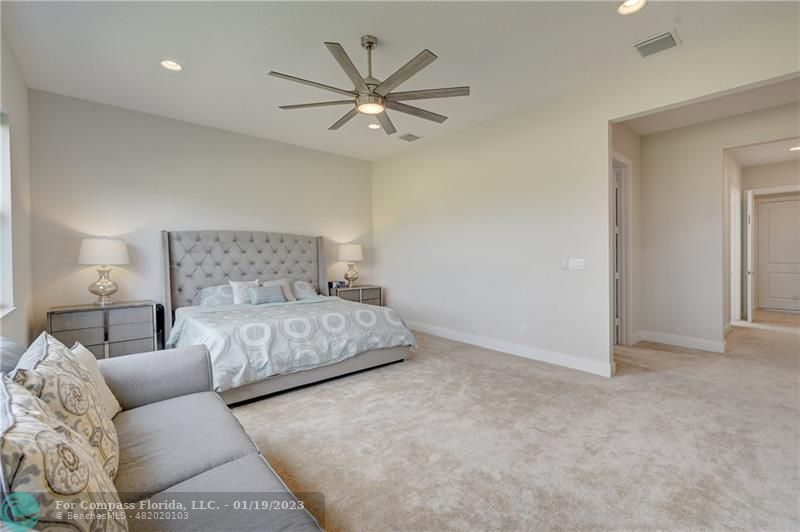 1000 Hookline Circle Loxahatchee, FL 33470 - Photo 29 of 98 a bedroom with a large bed chandelier and a ceiling fan