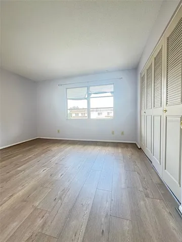 an empty room with wooden floor and window
