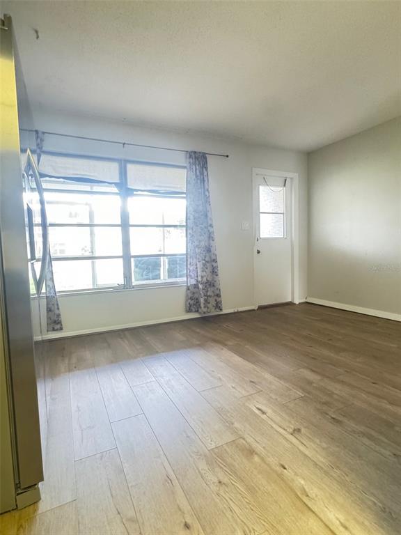 210 Elliot Avenue, Unit 135 Sarasota, FL 34232 - Photo 7 of 26 an empty room with wooden floor and windows