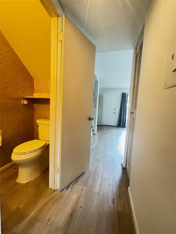 a bathroom with a toilet and a wooden floor