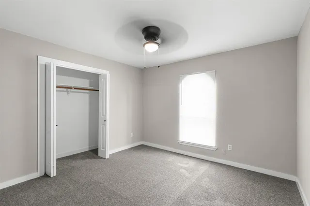 an empty room with a window and a ceiling fan