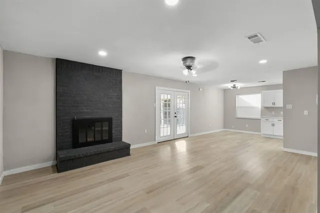 an empty room with wooden floor fireplace and windows