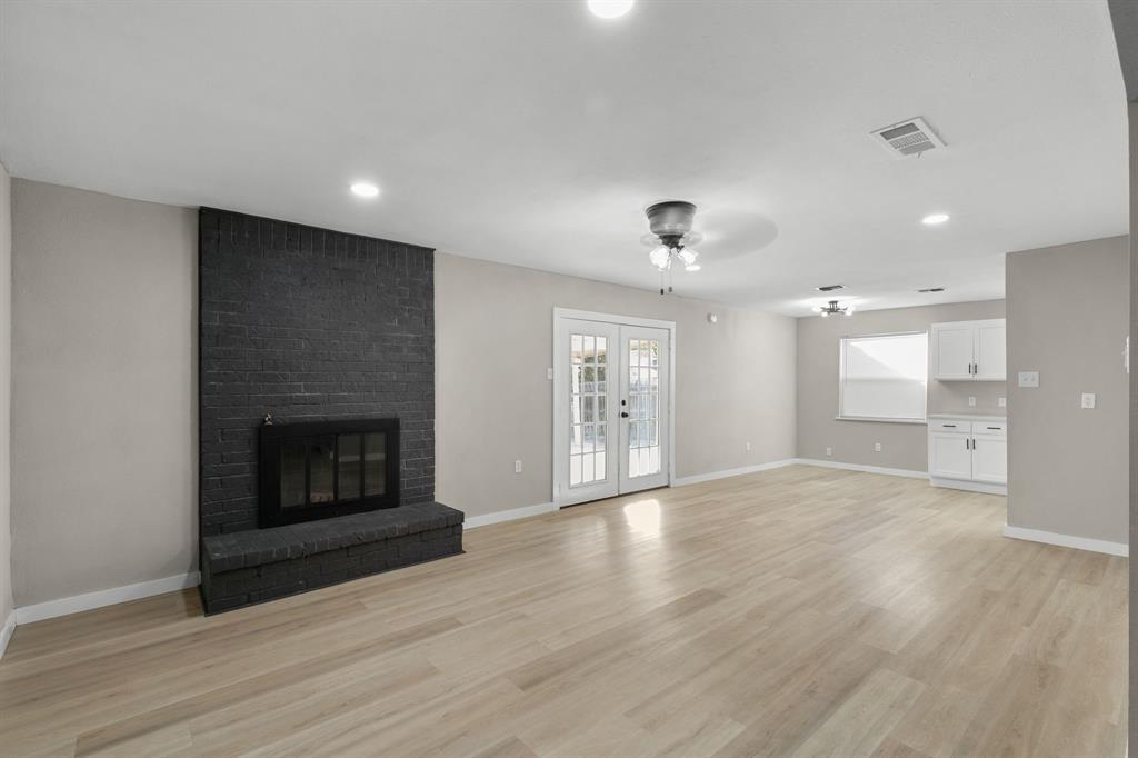 1002 Wembley Road Arlington, TX 76014 - Photo 3 of 20 an empty room with wooden floor fireplace and windows