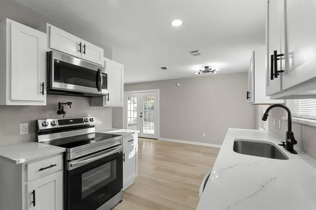 a kitchen with stainless steel appliances granite countertop a stove a sink and a microwave