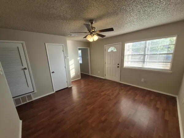 an empty room with wooden floor and a ceiling fan