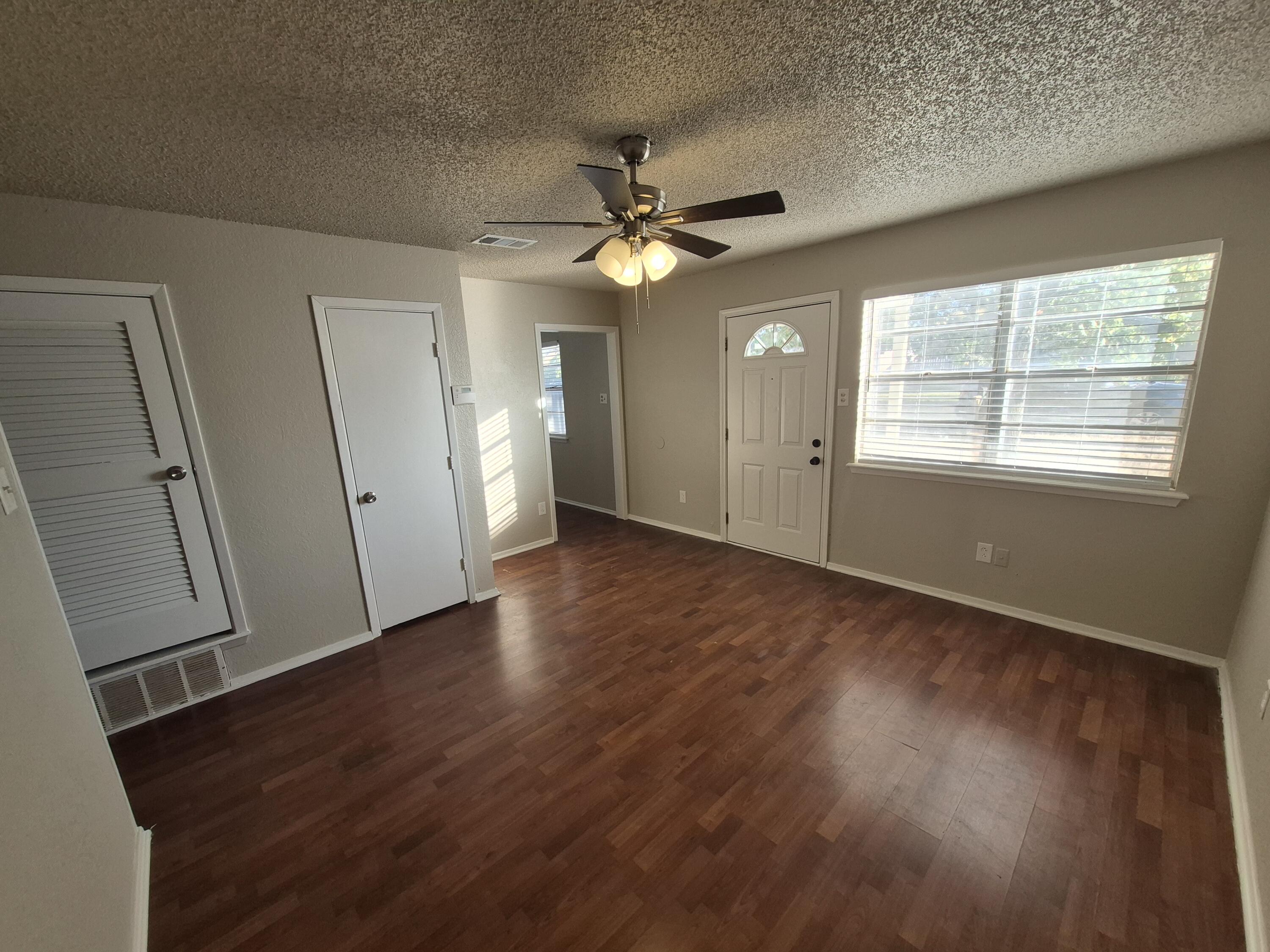 6404 28th Street Lubbock, TX 79407 - Photo 3 of 13 an empty room with wooden floor and a ceiling fan