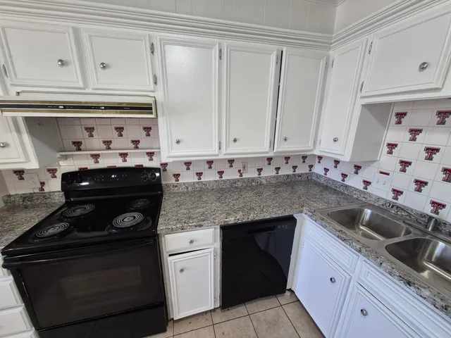 a kitchen with granite countertop white cabinets and stainless steel appliances
