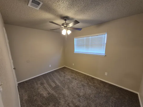 an empty room with a window and a fan