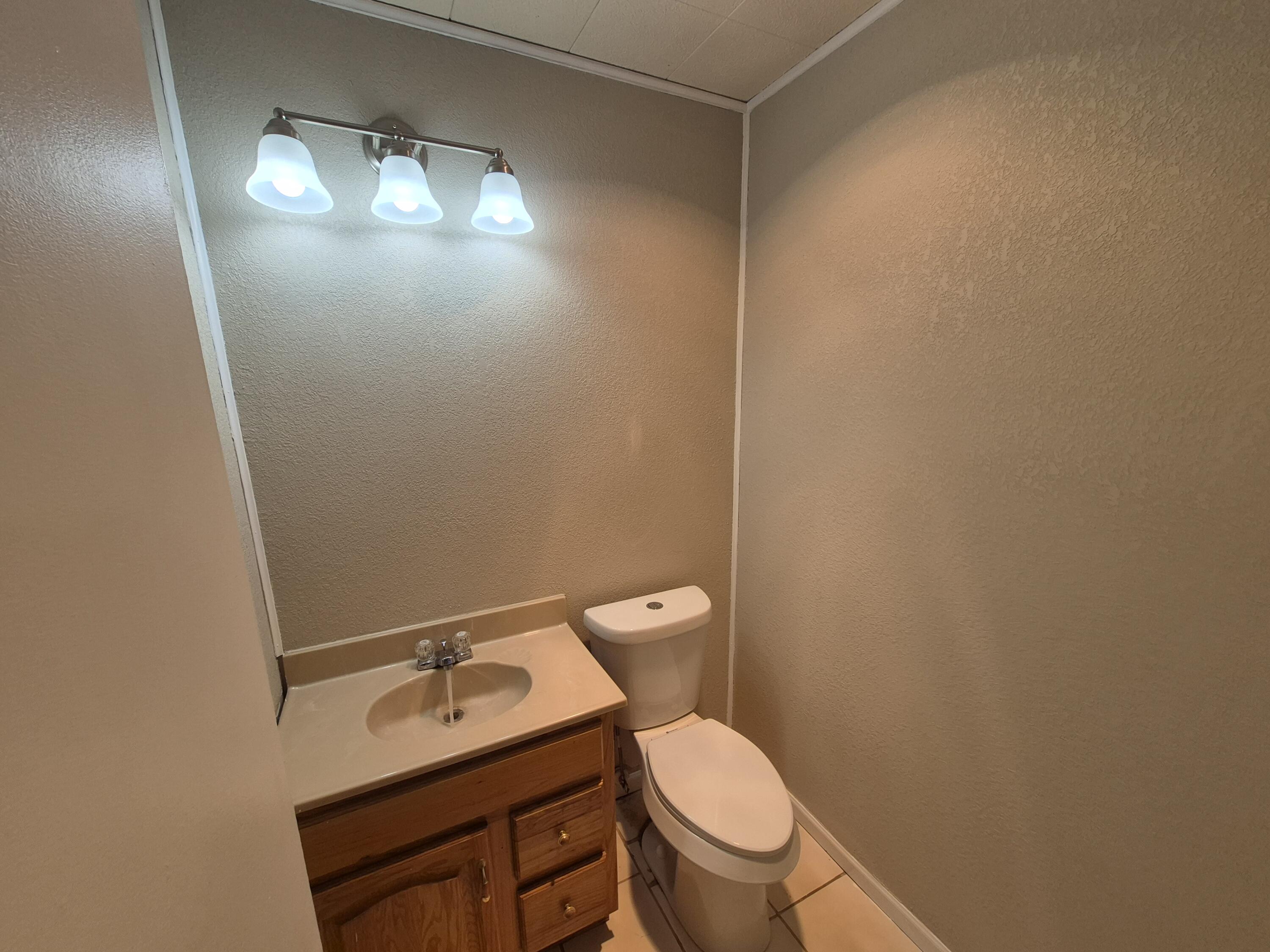 6404 28th Street Lubbock, TX 79407 - Photo 8 of 13 a bathroom with a toilet a sink and mirror